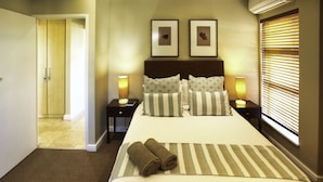A hotel room with a large bed, two bedside tables with lamps, a headboard, and a window with blinds. - Ellefsen Golf Suite 106 Langebaan 4-slpr (Langebaan)