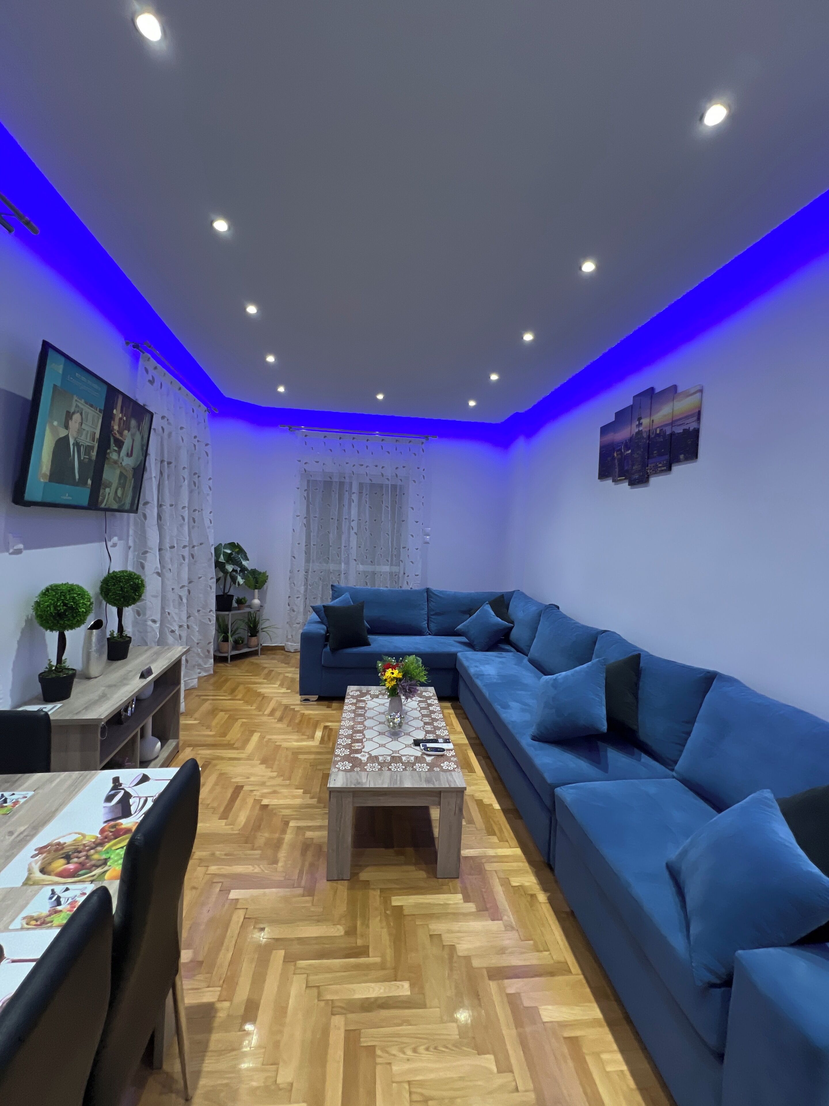 A modern living room with a blue sofa, a wooden coffee table, and a herringbone floor.
