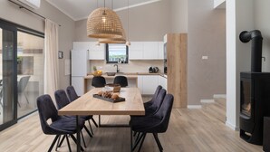 Eine moderne Küche mit Essbereich, ausgestattet mit einem Holztisch, schwarzen Stühlen und einer hängenden Leuchte.