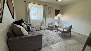 A living room with a gray sofa, two armchairs, a patterned rug, and a floor lamp. - Charming 3-bedroom house with AC and WiFi in delightful Phoenix (Phoenix)