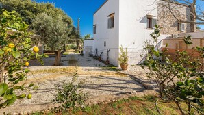 A white building with a stone facade, surrounded by greenery and a gravel courtyard. - 3740 AM Carrone - Appartamento 2 (Carovigno)