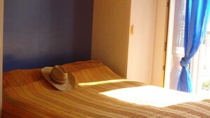 Una camera da letto con un letto, un cappello sul letto e una finestra con tende.