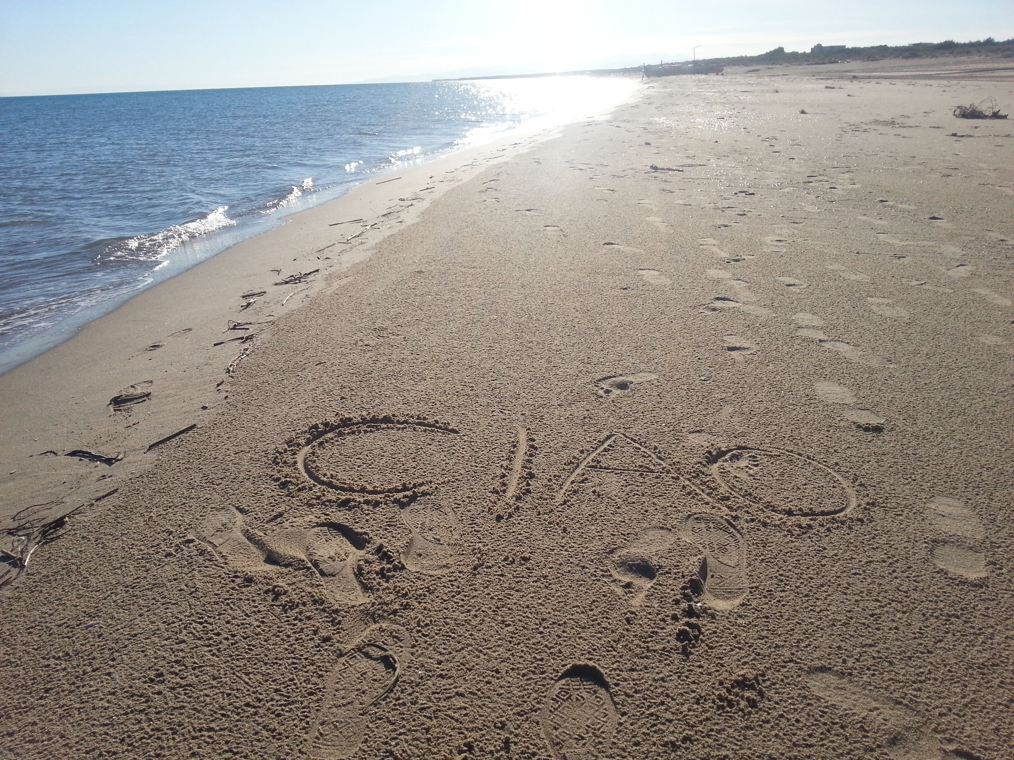 Una playa arenosa con huellas y un corazón dibujado en la arena.