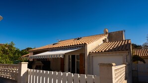 A residential building with a tiled roof, a satellite dish, and a white picket fence.