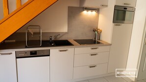 A compact kitchen with a dishwasher, stove, and sink.