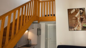 A kitchen with a wooden staircase, a refrigerator, and a sink.