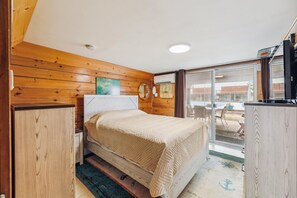 Un dormitorio con cama, paredes de madera, una ventana y vistas al exterior.