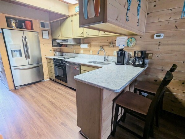Una cocina compacta con refrigerador, estufa, horno y pileta.