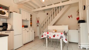 Una cucina con mobili bianchi, un forno a microonde, una macchina da caffè e un tavolo da pranzo con tovaglia rossa e bianca.