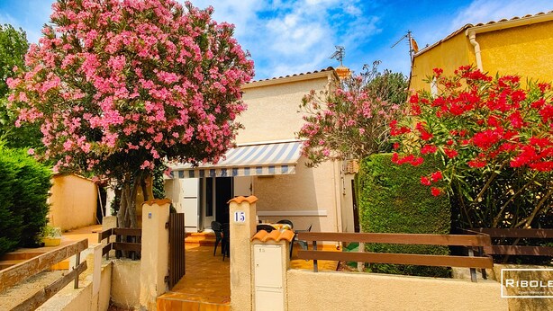 Una villa con patio, una panchina in legno e un cancello.
