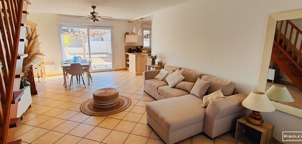Amplia sala de estar con un sofá seccional grande, comedor con mesa y sillas, y área de cocina con mostrador y armarios.