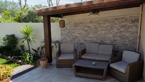 An outdoor patio with wicker furniture, a stone wall, and potted plants. - Riboleys - Villa avec clim et piscine privée (Vias)