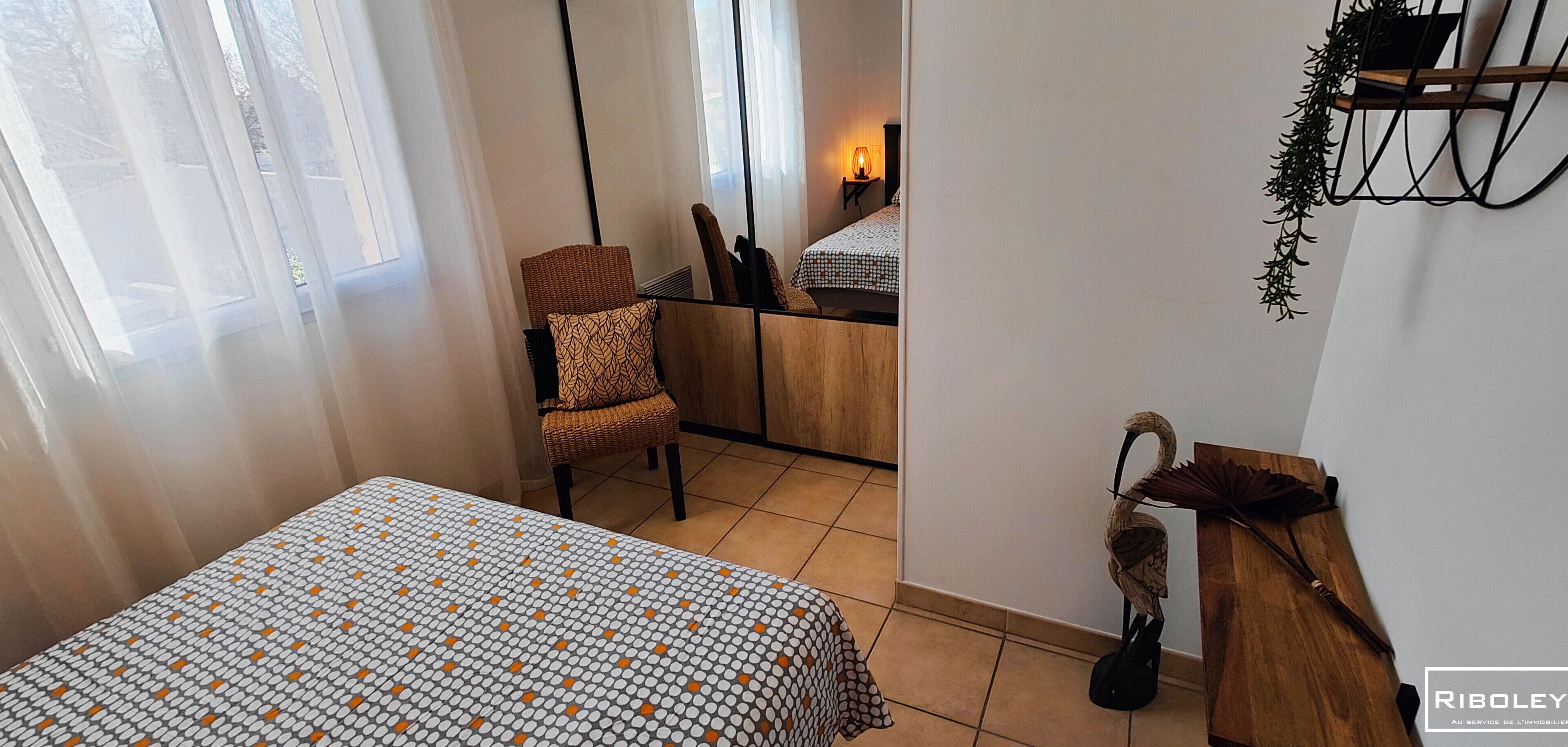 Een slaapkamer met een bed, een stoel, een bureau en een bijzettafeltje.