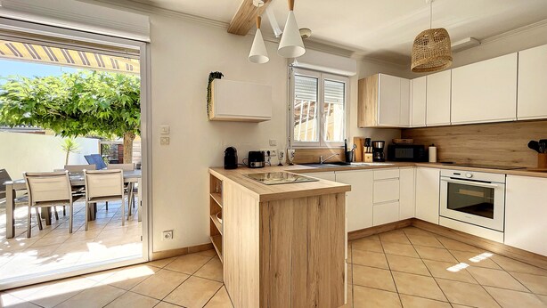 A modern kitchen with a wooden island, white cabinets, and a large window. - Riboleys - Villa avec clim et piscine privée (Vias)