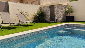 A swimming pool with a tiled edge, surrounded by a well-maintained lawn and a stone wall. - Riboleys - Villa avec clim et piscine privée (Vias)