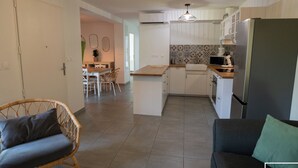 Eine moderne Küche mit weißen Schränken, einem eingebauten Ofen und einem Kühlschrank. Es gibt einen Essbereich mit Tisch und Stühlen.