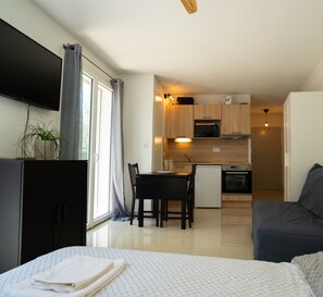 Cozy living space with a flat-screen TV, dining area, and kitchenette featuring a microwave, refrigerator, and stove.
