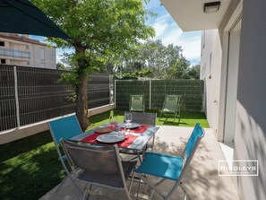 Enjoy a romantic meal for two on the patio, surrounded by lush greenery and a shaded tree.
