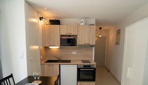 Compact kitchen with appliances, under-cabinet lighting, and a dining area with table and chairs.