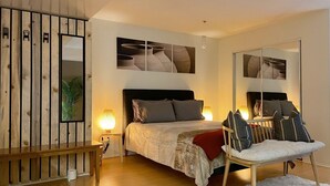Ein Schlafzimmer mit Bett, Nachttischen, einem Sessel, einem Spiegel und Bildern an der Wand.