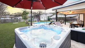 Un pati amb un banyera d'hidromassatge, mobles d'exterior i una piscina.