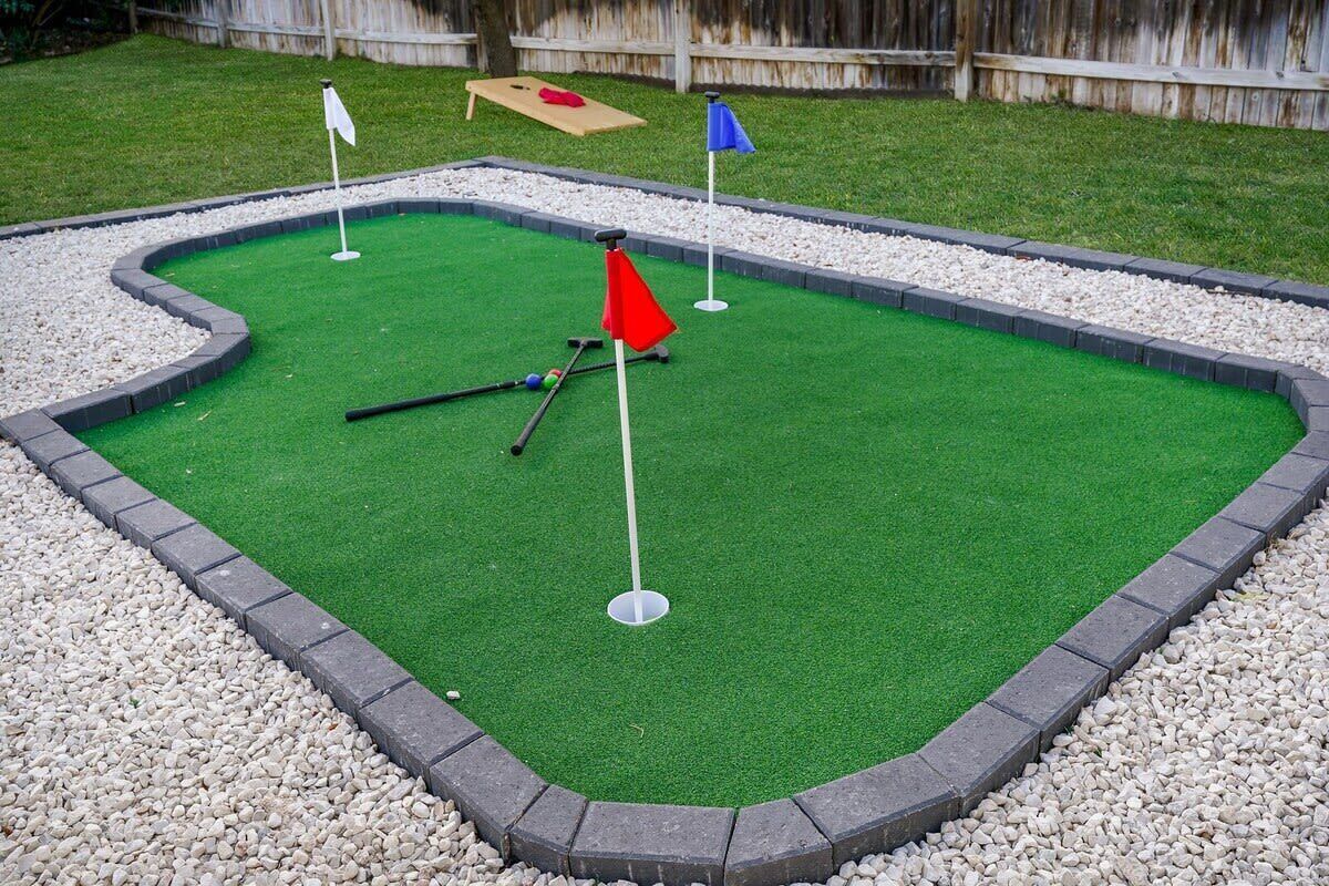Un parcours de mini-golf avec un gazon artificiel vert, un drapeau rouge et un drapeau bleu.