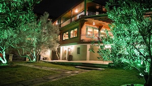 Un edificio de dos pisos con un balcón, un sendero de piedra y una entrada bien iluminada.