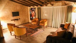 Un salón acogedor con suelo de madera, un sofá de cuero marrón, dos sillones amarillos, una mesa de centro de madera y una alfombra a rayas.