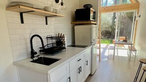 Een moderne keuken met witte kastjes, een zwarte kraan en houten balken. Er is een raam dat natuurlijk licht en uitzicht op de omgeving biedt.