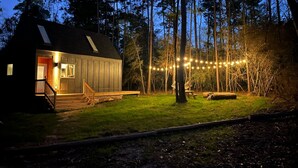 Een houten hut met een veranda en een lichtslingering in een bebost gebied.
