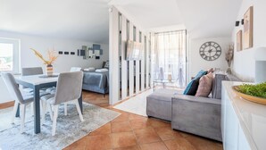 Una sala de estar moderna con comedor, sofá gris y televisor montado en la pared.