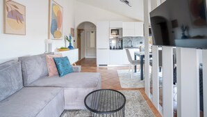 Una sala de estar moderna con un sofá gris, una mesa de centro redonda y un televisor de pantalla plana.