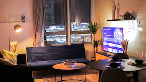 Una sala moderna con un sofá, una mesa de centro y un televisor sobre un mueble.