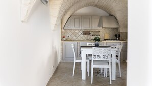A kitchen with white cabinets, a tiled backsplash, and a stone archway.