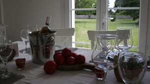Ein Esstisch mit einer Flasche, Gläsern und einer Tomatenschale.