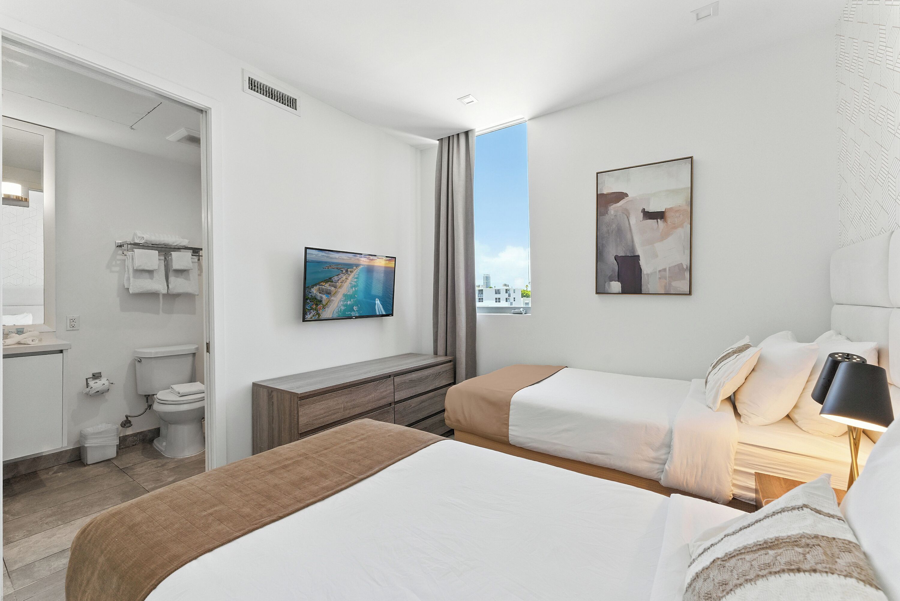 A hotel room with a large bed, a bedside table with a lamp, a TV, and a painting.