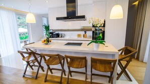 A modern kitchen with a central island, wooden chairs, and pendant lighting. - Villa Visnja - Private villa with pool, Dalmatia (Stikovica)