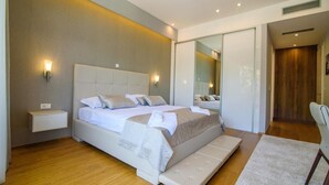 A modern bedroom with a large bed, bedside tables, a mirror, and a wooden floor. - Villa Visnja - Private villa with pool, Dalmatia (Stikovica)