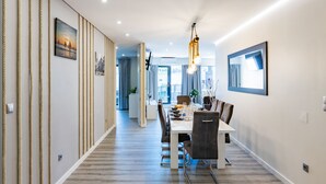 A modern dining area with a long table, chairs, and a hanging light fixture.