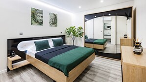 A modern bedroom with a wooden bed, green bedding, a large mirror, and a plant.