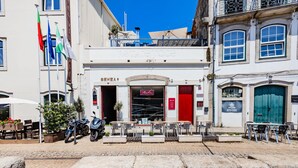 A building with a red door and a sign that reads "SEVEA". There are outdoor tables and chairs in front of the building.