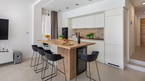 A modern kitchen with a central island, bar stools, a flat-screen TV, and a built-in oven. - Villa Dragica - Private villa with pool, Sibenik (Zaboric)