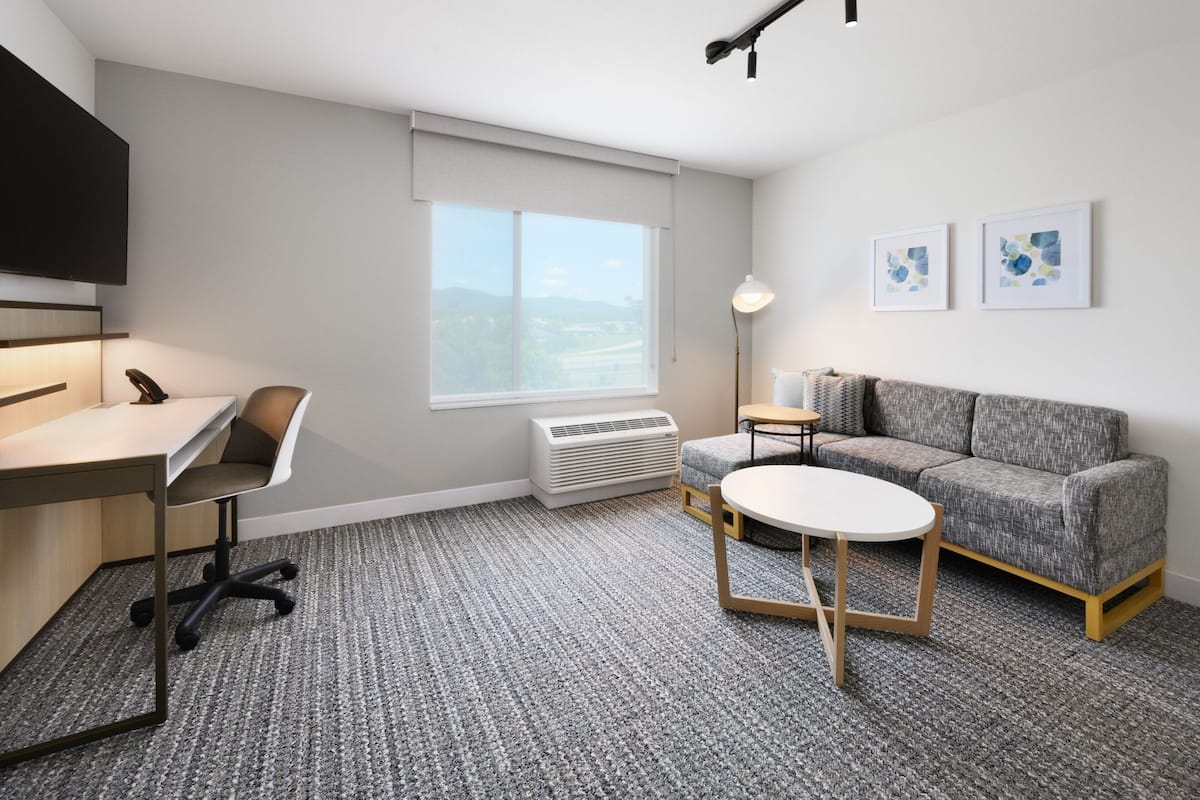 Une chambre d’hôtel moderne équipée d’un bureau, d’une chaise, d’un canapé et d’une petite table.