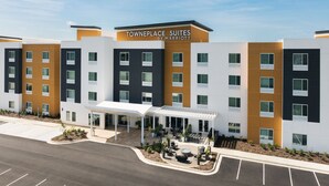A modern hotel with a covered outdoor seating area and a parking lot.