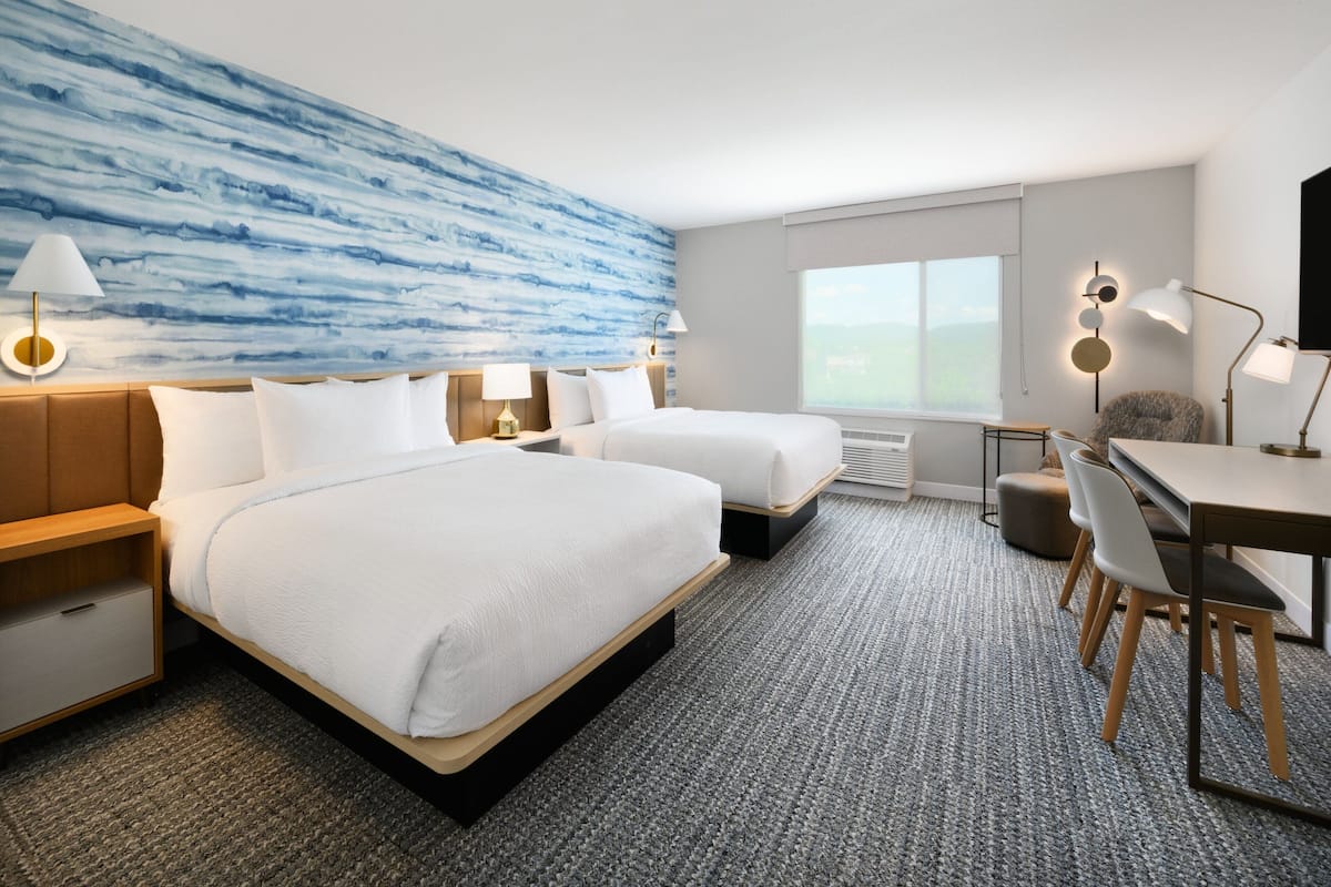 Une chambre d’hôtel avec deux lits, un bureau et une chaise.
