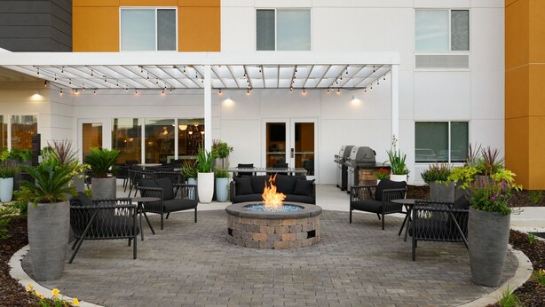 An outdoor patio with a fire pit, seating, and planters.