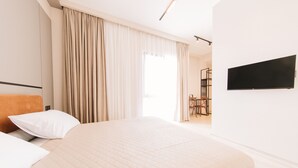 A hotel room with a large bed, a flat-screen TV mounted on the wall, and a view of the room's interior through a window with curtains. - Doors Hotel (Tbilisi)