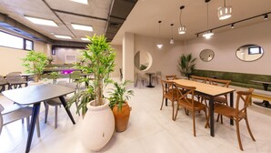 A modern dining area with tables and chairs, potted plants, and pendant lighting. - Doors Hotel (Tbilisi)
