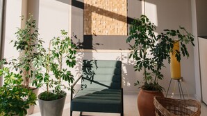 A modern interior with a green chair, potted plants, and a woven basket. - Doors Hotel (Tbilisi)