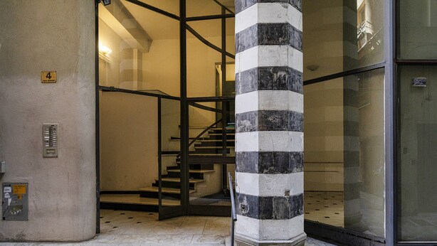 A staircase with a black and white striped column, a glass door, and a number '4' sign on the wall. - City and the Sea in Genova (Genoa)